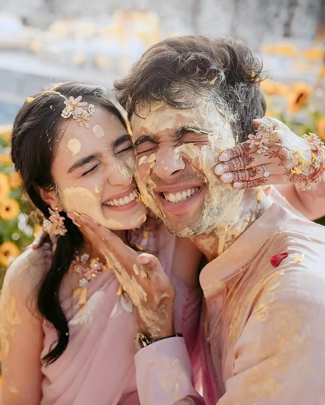 Joyful candid shot of a couple covered in turmeric paste during a Haldi ceremony, showcasing emotional luxury wedding photography.