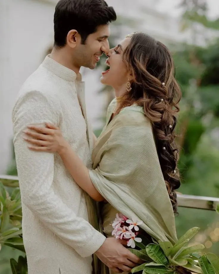 Fine-art wedding photography of an intimate candid moment between a bride in a pastel saree and a groom in an ivory sherwani.